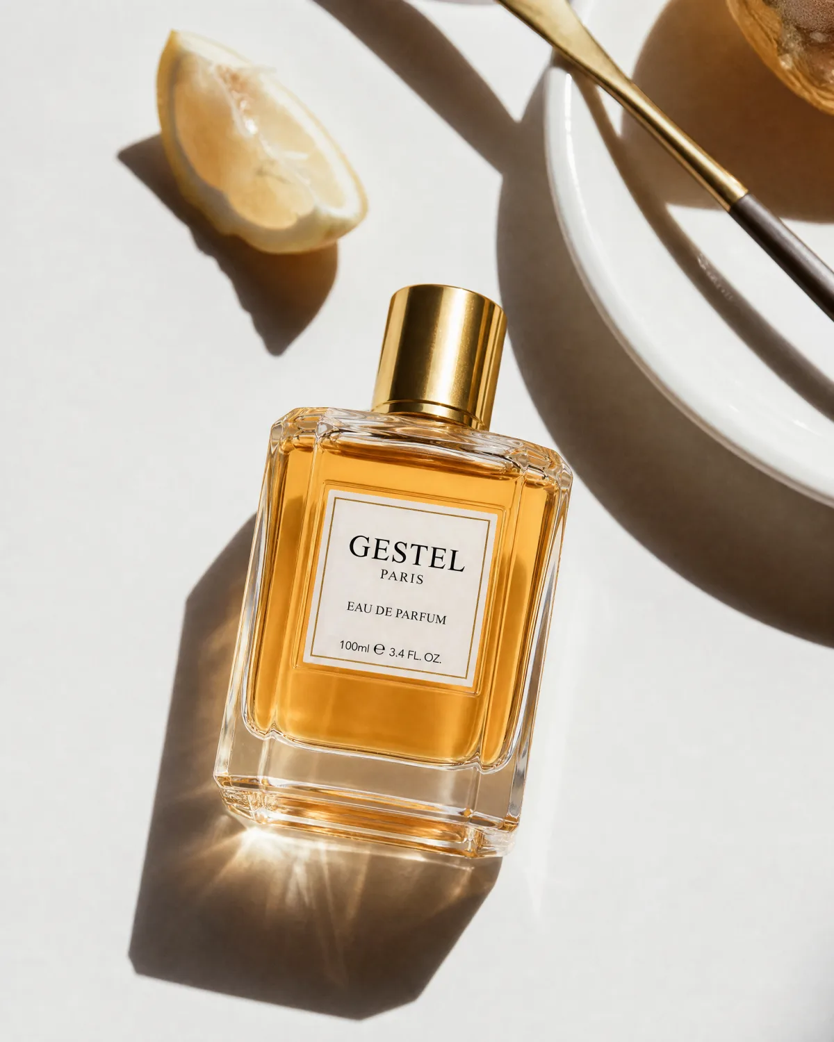GESTEL perfume bottle in bright sunlight with citrus, spoon, and ceramic plate styling.